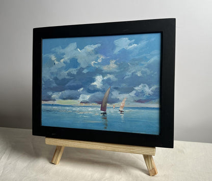 Black-framed oil painting of sailboats on blue sea by Yuriy Suprunchuk