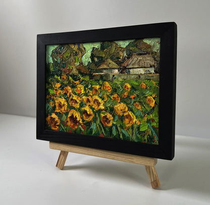 Oil painting Sunny day in the village by Oksana Ivanyuk, vibrant sunflowers in black frame on easel