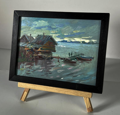 Framed oil painting of serene lakeside houses on water by Yuriy Suprunchuk