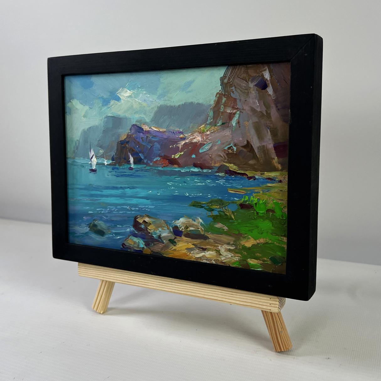 Black-framed miniature oil painting of sailboats on sea by Yuriy Suprunchuk on easel