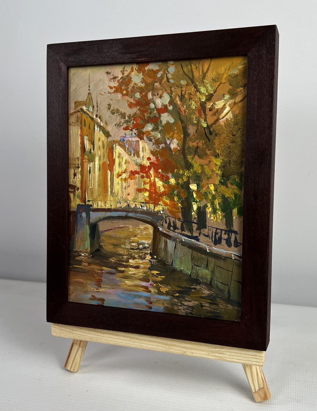 Dark wood-framed oil painting of autumn canal park by Yuriy Suprunchuk on easel