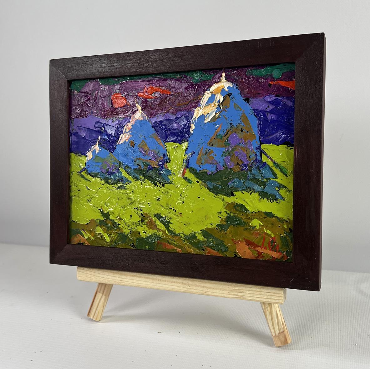 Oil painting by Oleksiy Ivanyuk: blue mountains, purple sky, green foreground in dark frame