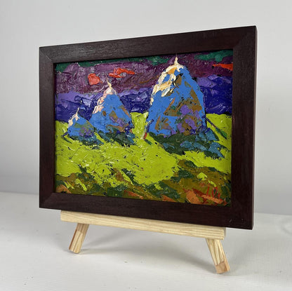 Oil painting by Oleksiy Ivanyuk: blue mountains, purple sky, green foreground in dark frame