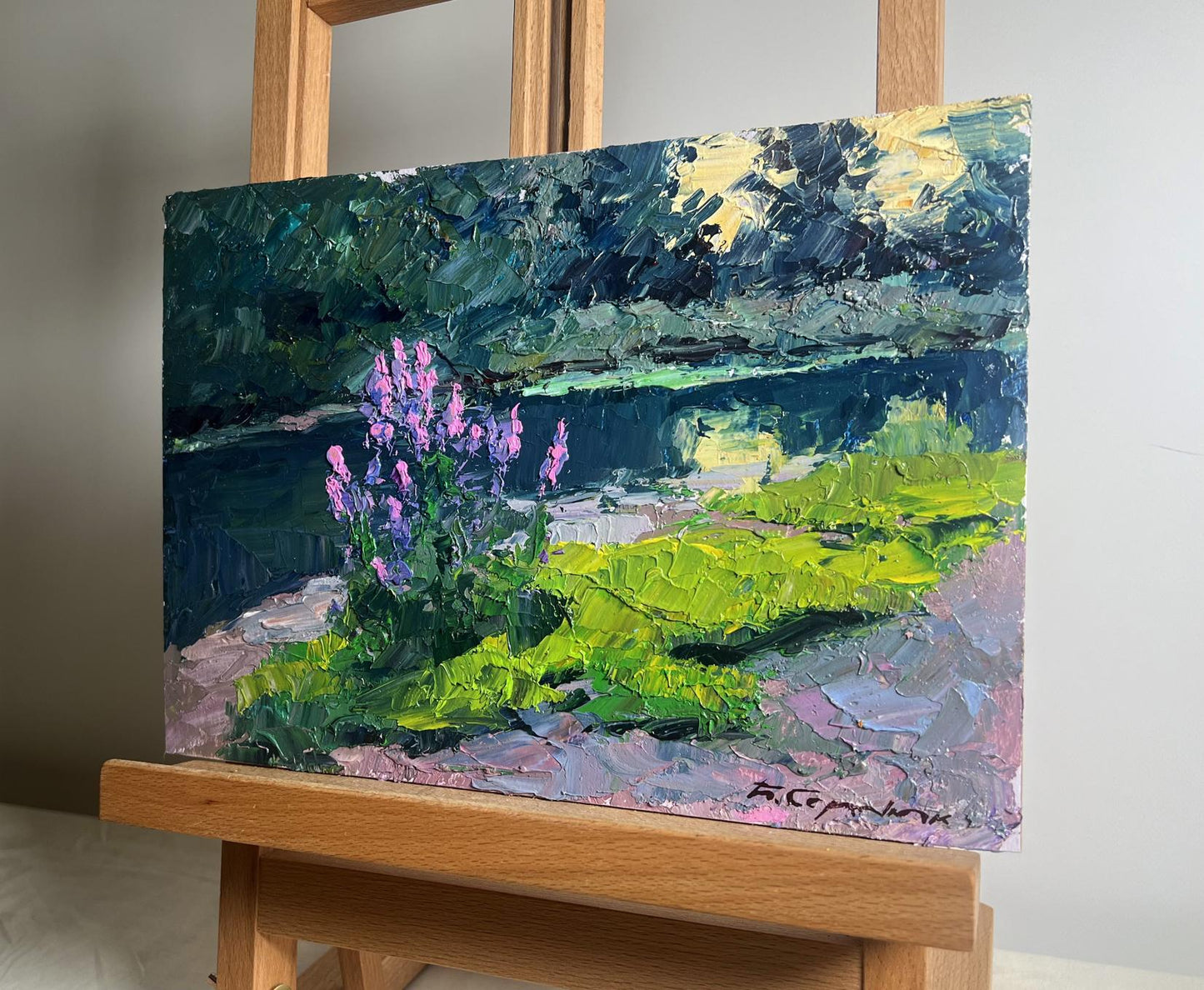 Vibrant impressionist oil painting of purple flowers, green fields near summer river by Boris Serdyuk on wooden easel