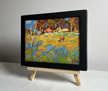 Oil painting of cow in field near village by Oksana Ivanyuk, vibrant yellows and blues