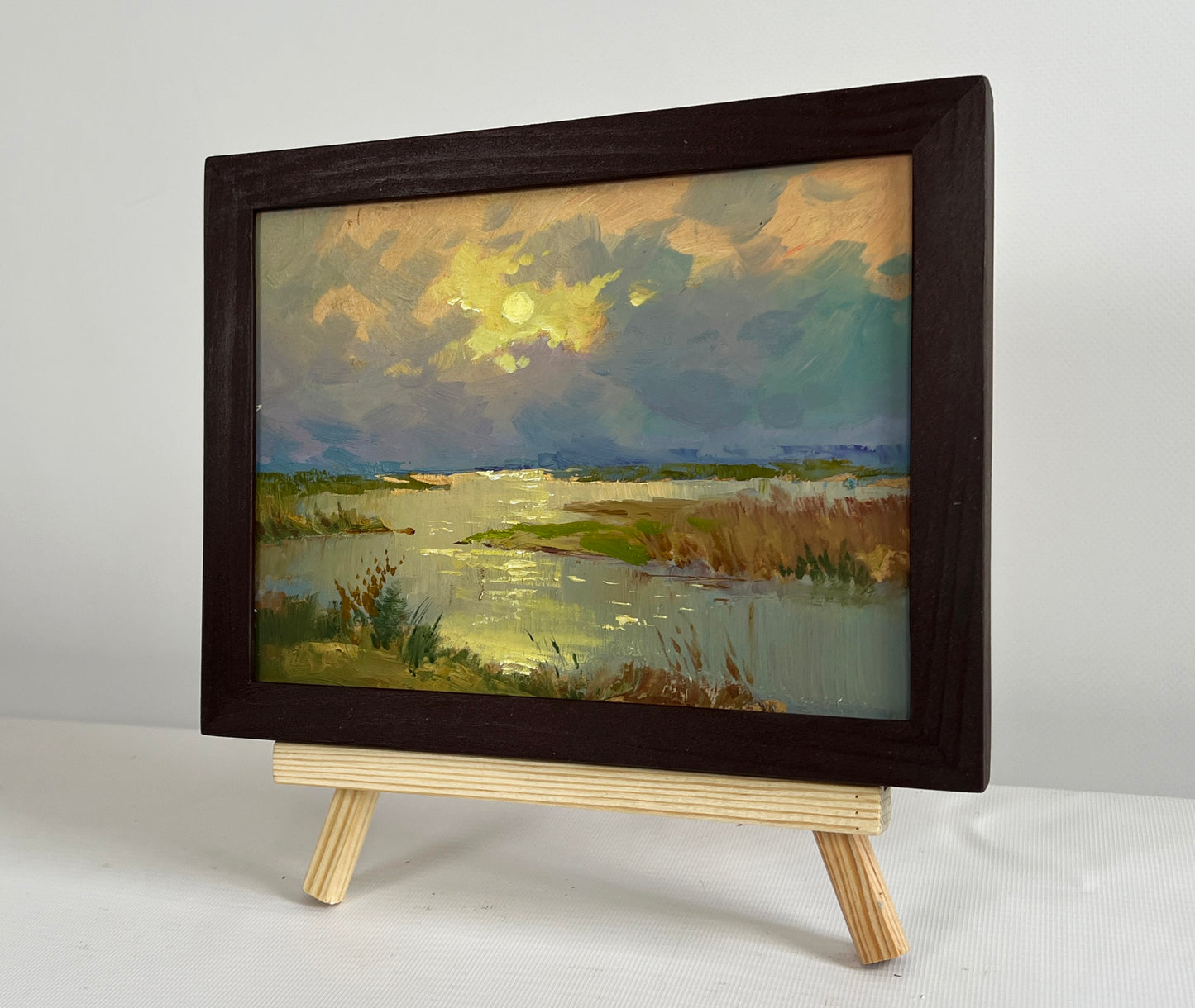 Oil painting The sun says goodbye to the horizon by Yuriy Suprunchuk in dark frame on easel