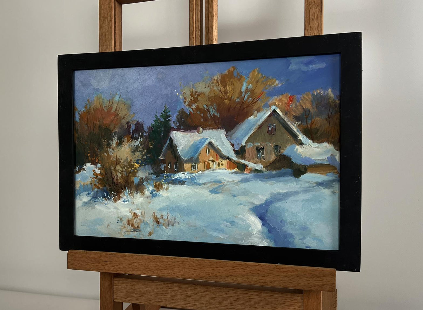 Oil painting by Yuriy Suprunchuk: snow-covered houses in black frame