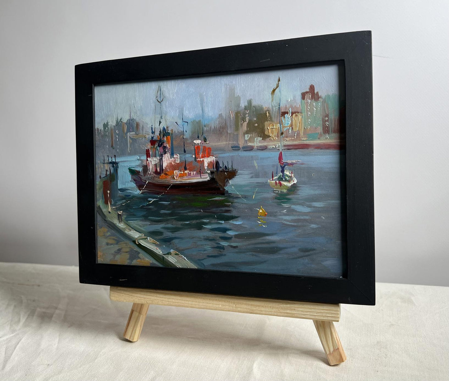 Black-framed oil painting of ship at pier by Yuriy Suprunchuk