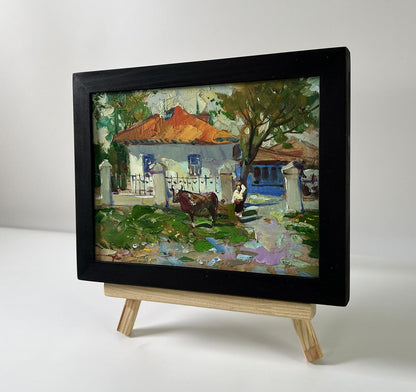 Oil painting by Yuriy Suprunchuk: cow near orange-roofed house