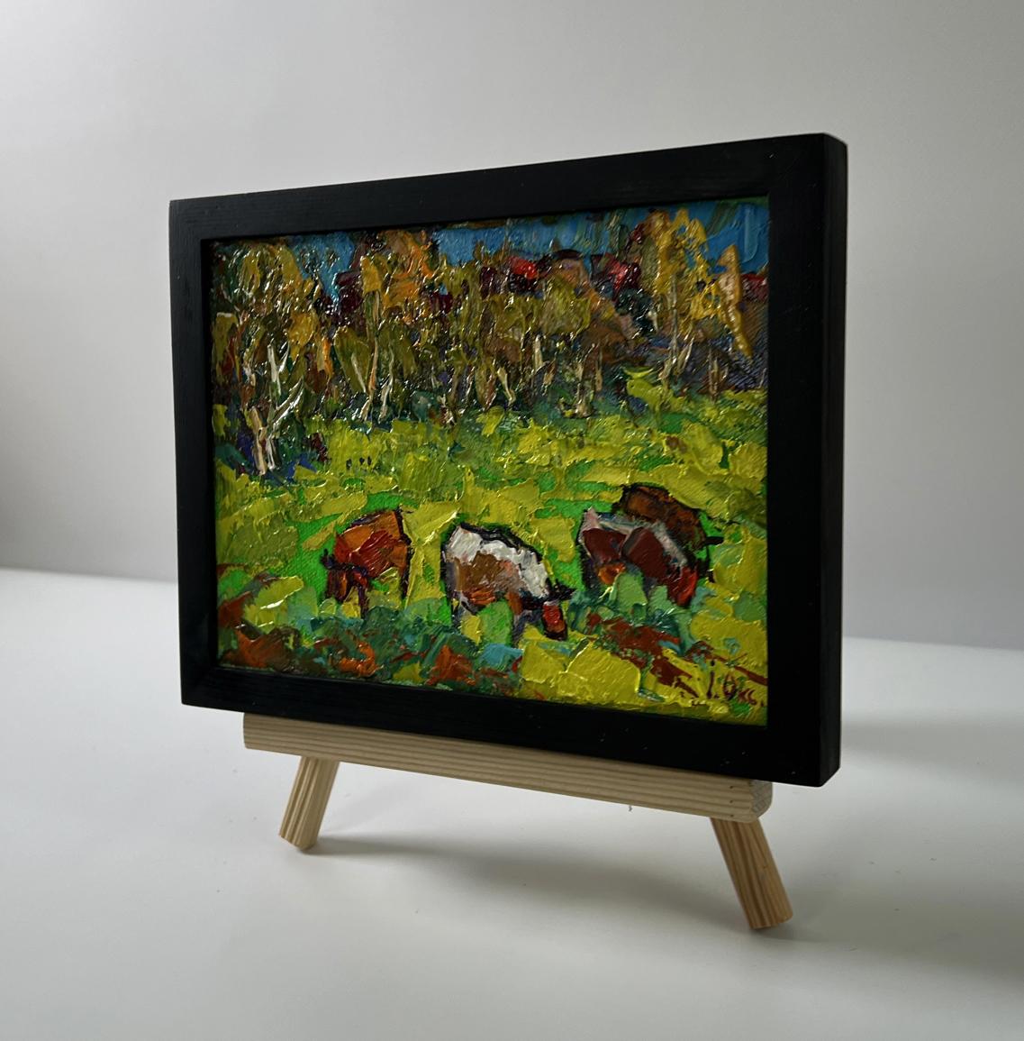 Oil painting of cows grazing in meadow by Oksana Ivanyuk in black frame
