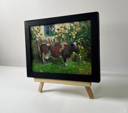 Framed oil painting of brown white cow near house by Yuriy Suprunchuk