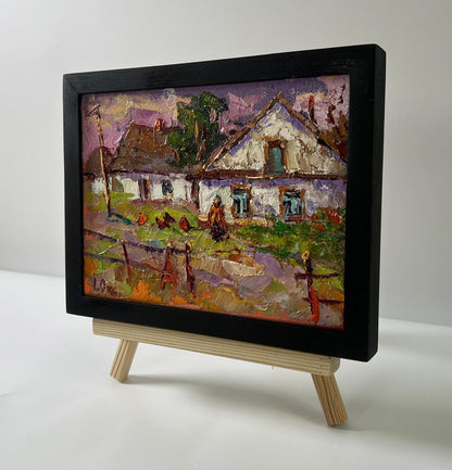 Oil painting of pink sunset over Oksana Ivanyuk village with white houses, chickens on easel