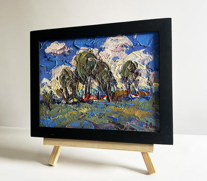Oil painting by Oksana Ivanyuk: Clouds over village, impasto blue skies, green trees