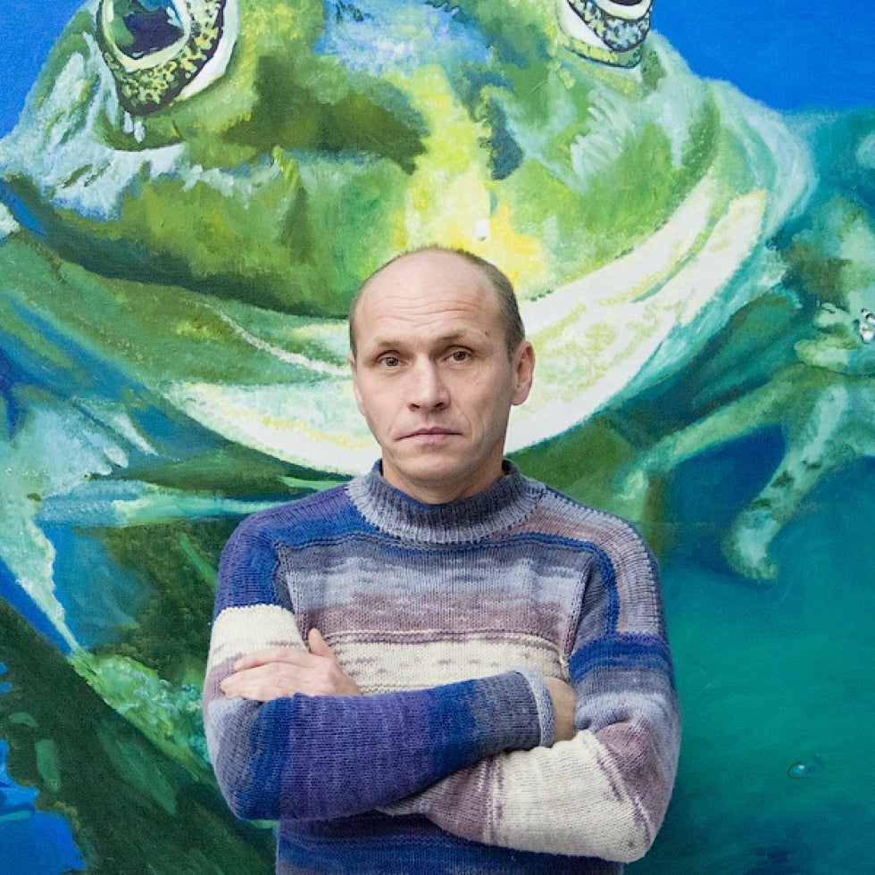 A man wearing a knitted sweater with horizontal stripes of blue, purple, and cream.