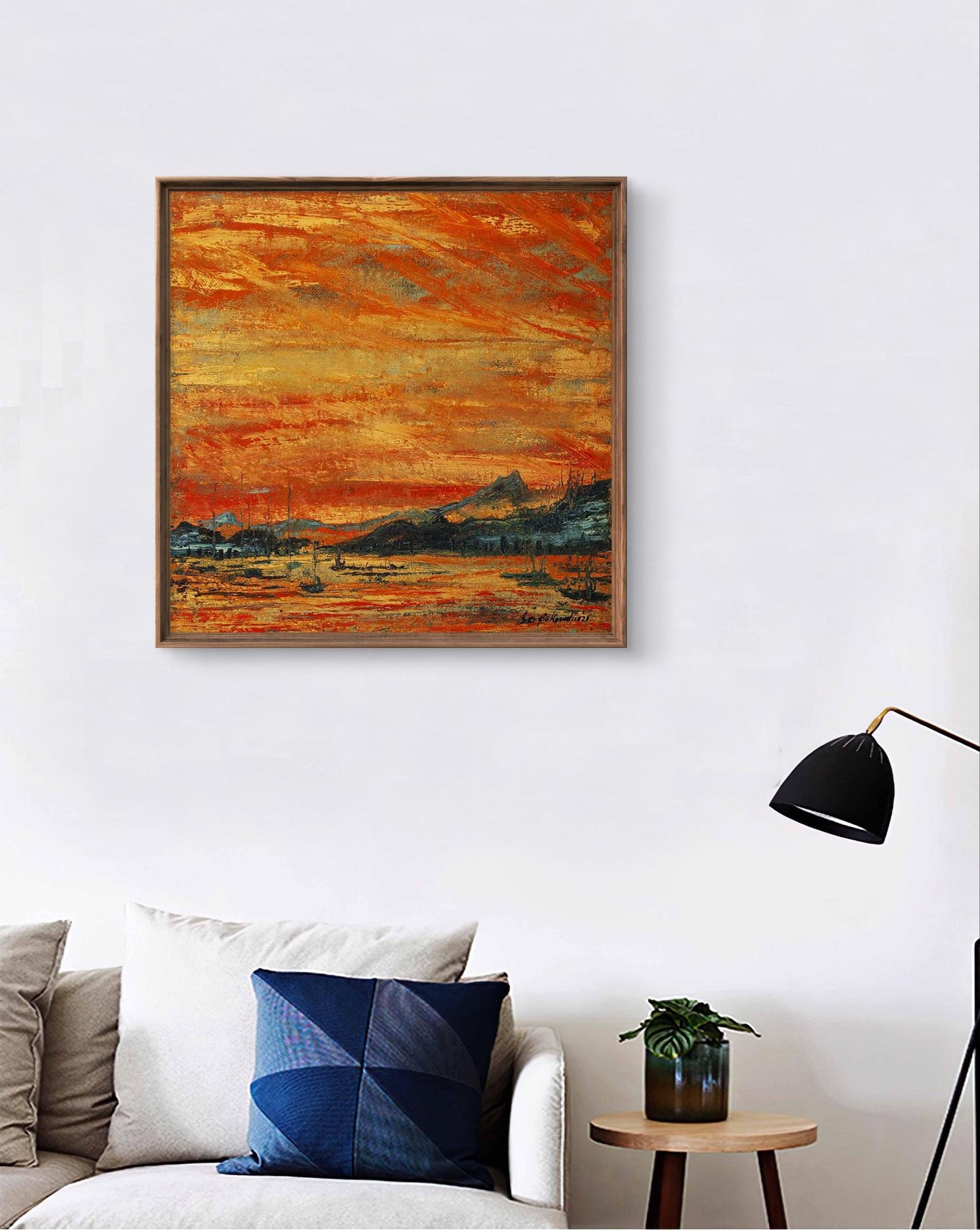 A square-framed abstract painting with vibrant orange and yellow brushstrokes depicting a sunset landscape, set in a wooden frame.