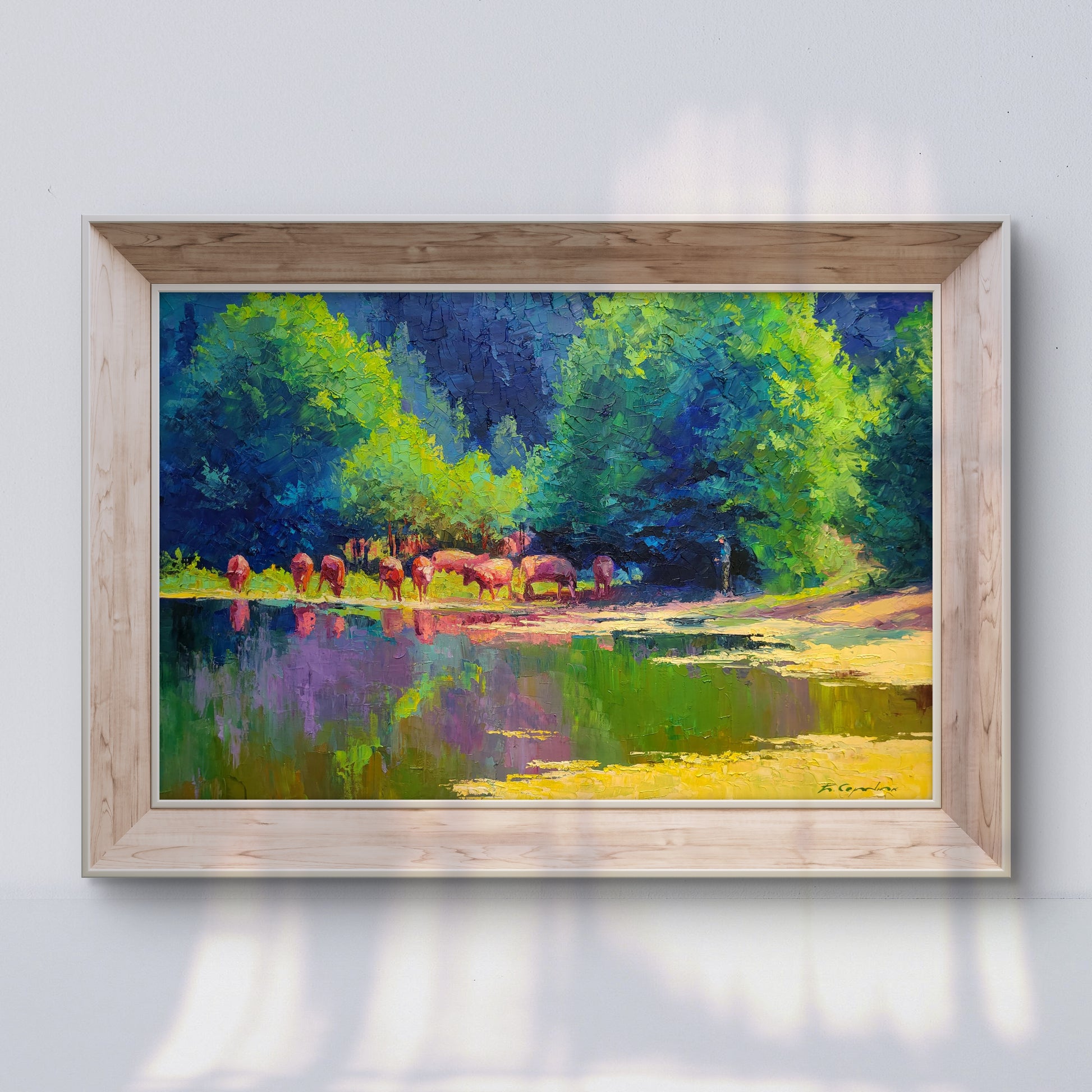 A vibrant impressionist painting in a light wood frame depicts a herd of reddish-brown cattle standing by a reflective pond surrounded by lush green and blue trees.