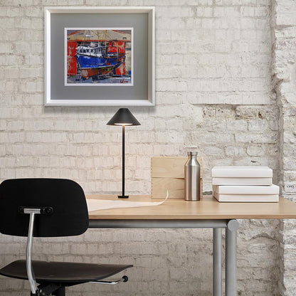 White-framed oil painting of blue boat on red orange walls by Volodymyr Gluhomanyuk