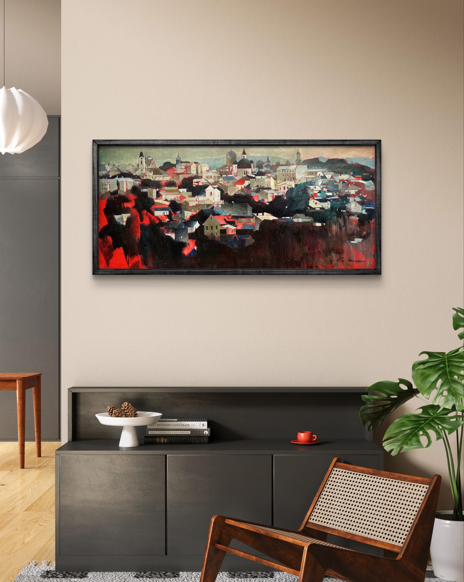 A framed abstract cityscape painting with bold red and dark tones, housed in a sleek black frame.