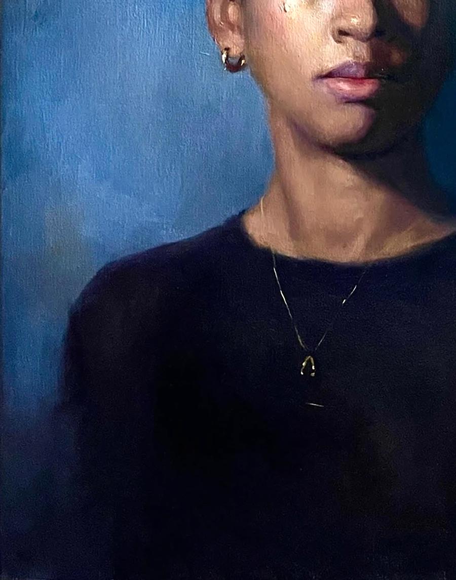 Delicate gold wishbone pendant on chain over black top in Ruby Annam Butt portrait