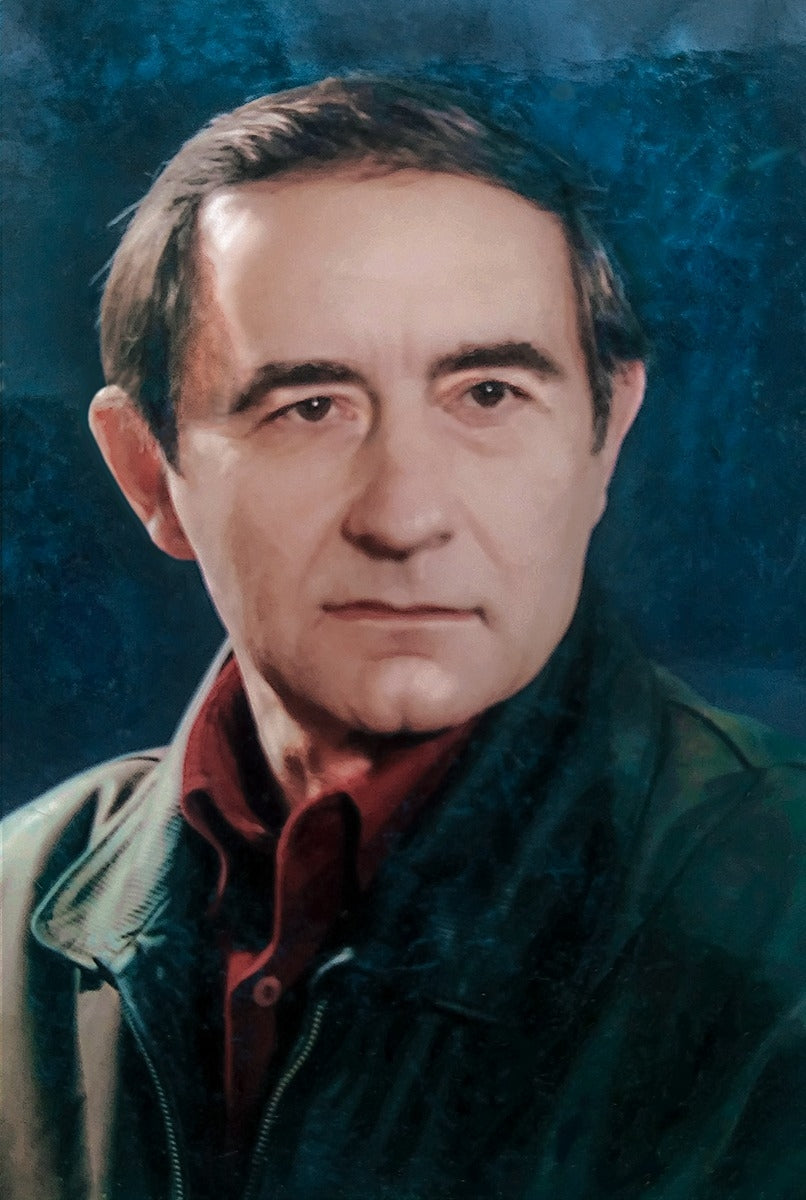 A man with dark hair and a serious expression, wearing a dark green jacket over a red collared shirt.
