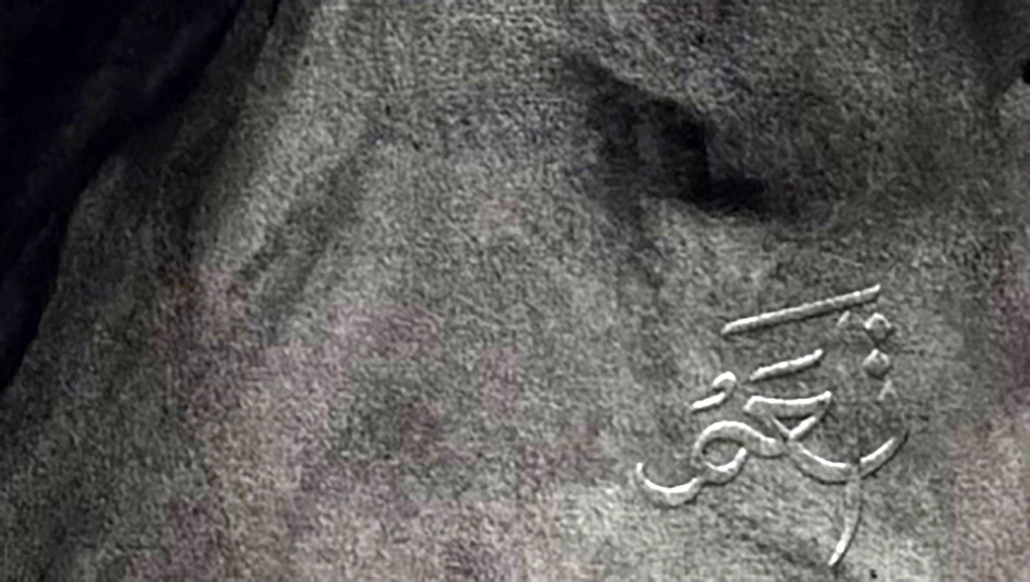 Silver Arabic script engraved on gray stone back of Mariia Annam Butt portrait
