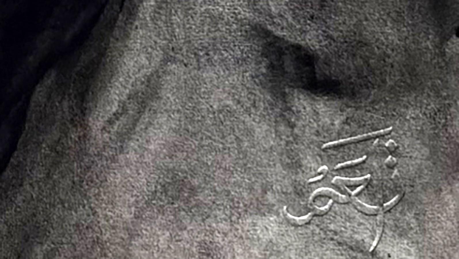 Silver Arabic script engraved on gray stone back of Mariia Annam Butt portrait