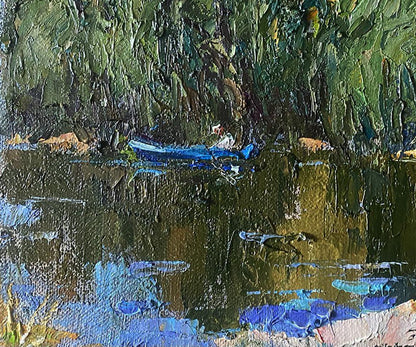 A vibrant blue rowboat rests gently on a reflective, textured water surface beneath lush green foliage.