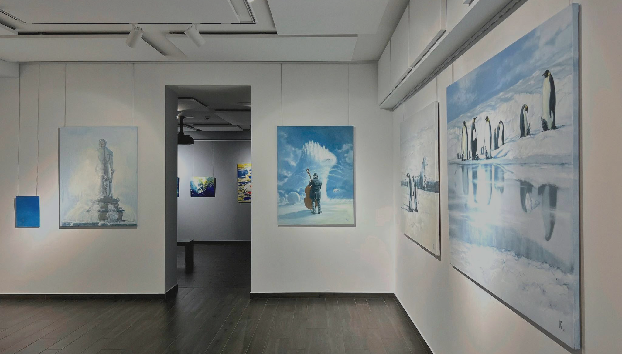 A large, framed painting depicting a group of penguins standing on ice with their reflection in the water below.