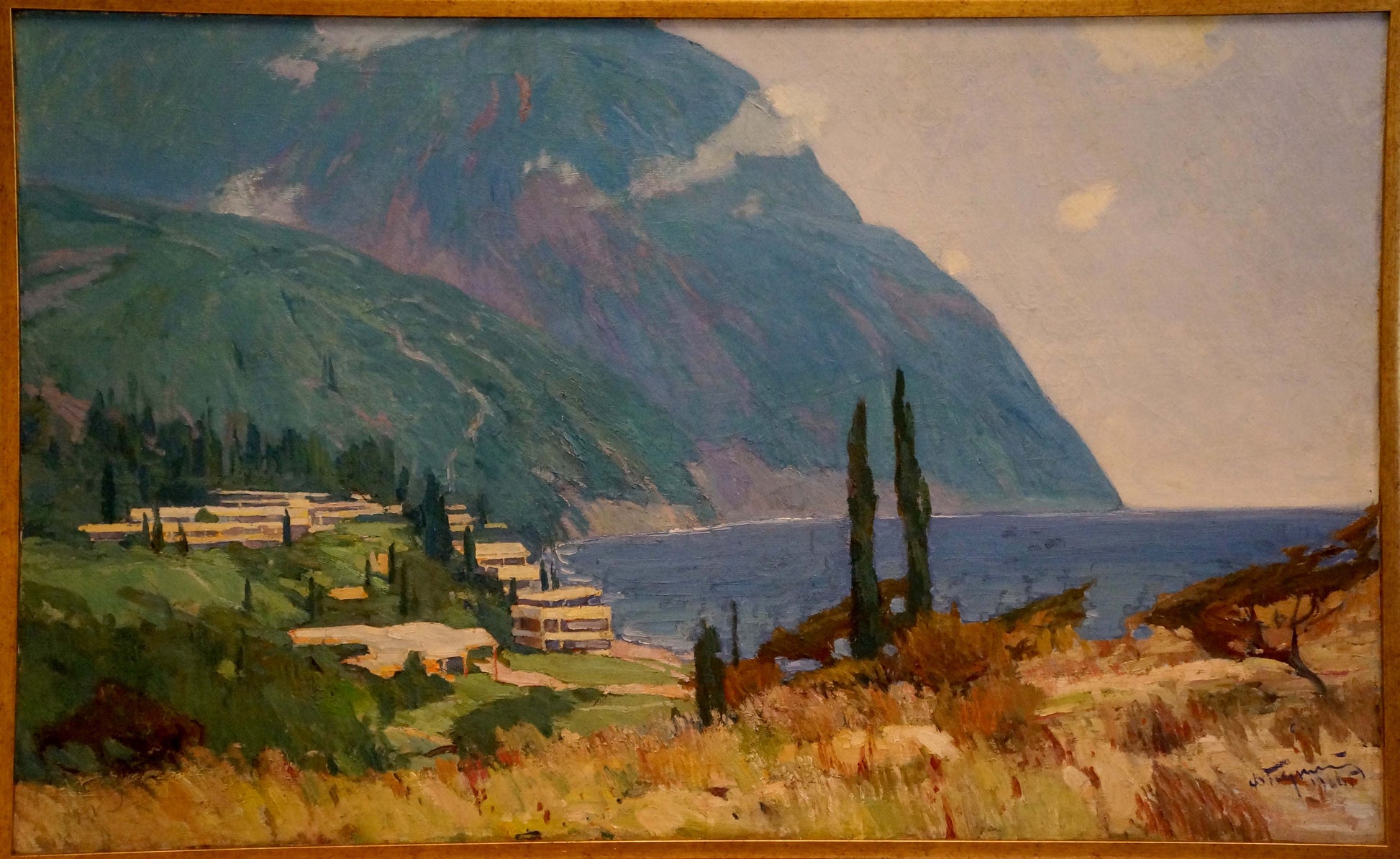 Framed oil painting of coastal city with green mountains and cypress trees