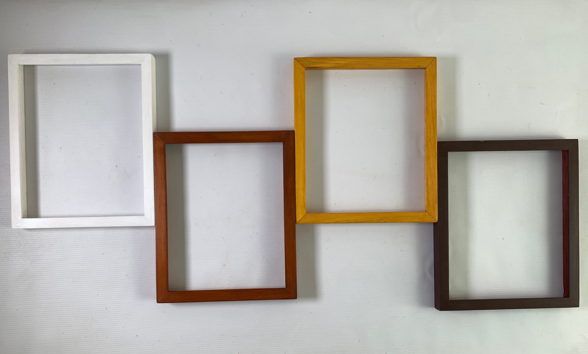 Four custom wooden frames in white, brown, oak, espresso on wall