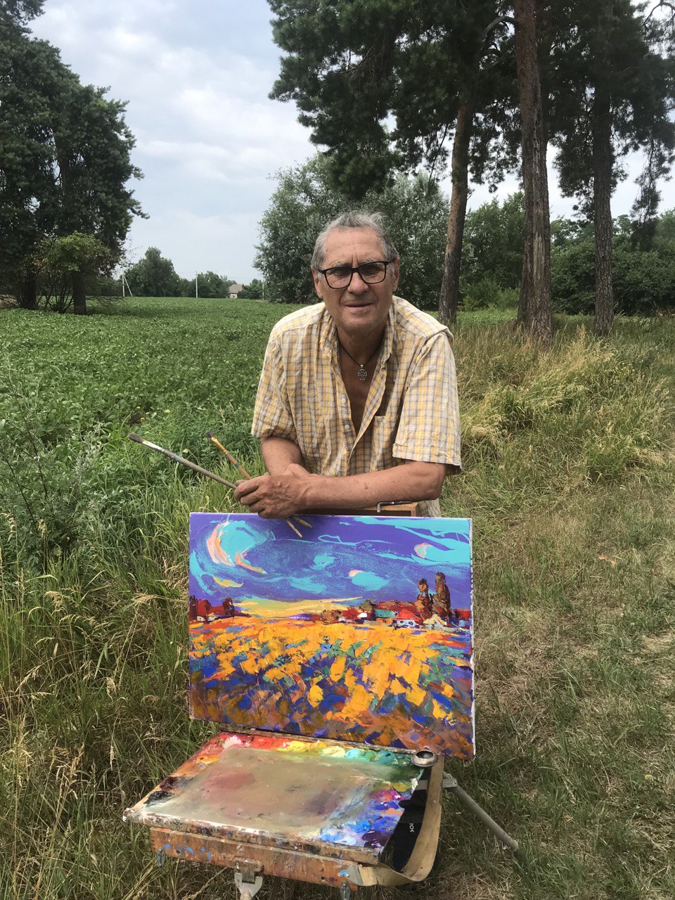 A vibrant, impressionistic landscape painting featuring a golden field under a swirling purple and blue sky with two figures in the distance.