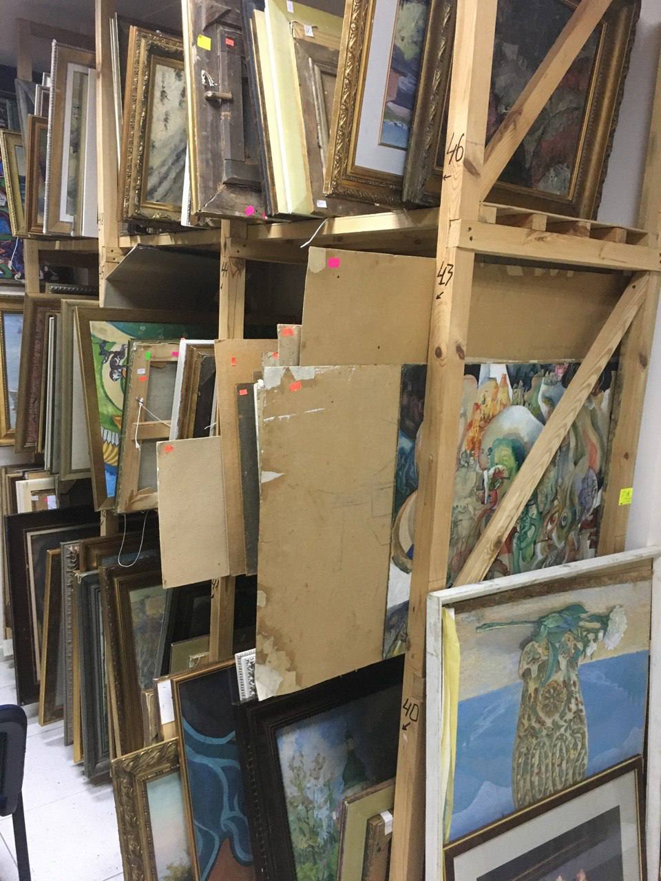Stacked wooden easels with wholesale framed paintings in ornate gold frames