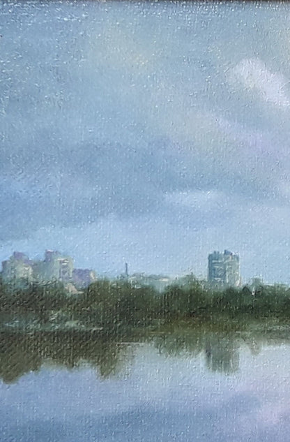 Oil painting by Korkishko Vasily: blue-gray sky, clouds over water reflecting city skyline