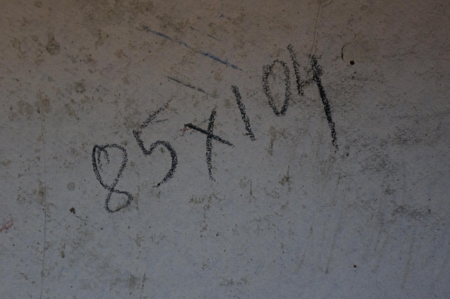 Black chalk markings on textured light gray concrete wall of oil painting