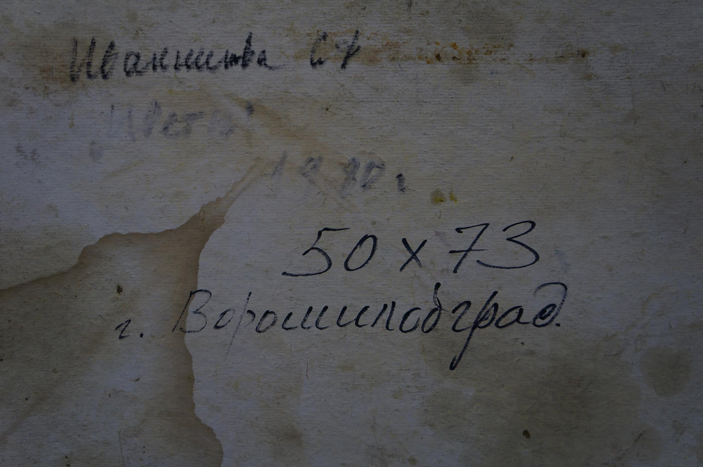 Back of Ivannikova S.R. oil painting with faded black handwritten markings on weathered plaster wall