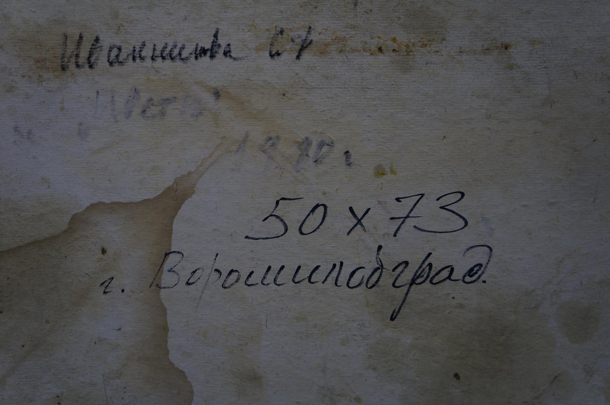 Back of Ivannikova S.R. oil painting with faded black handwritten markings on weathered plaster wall