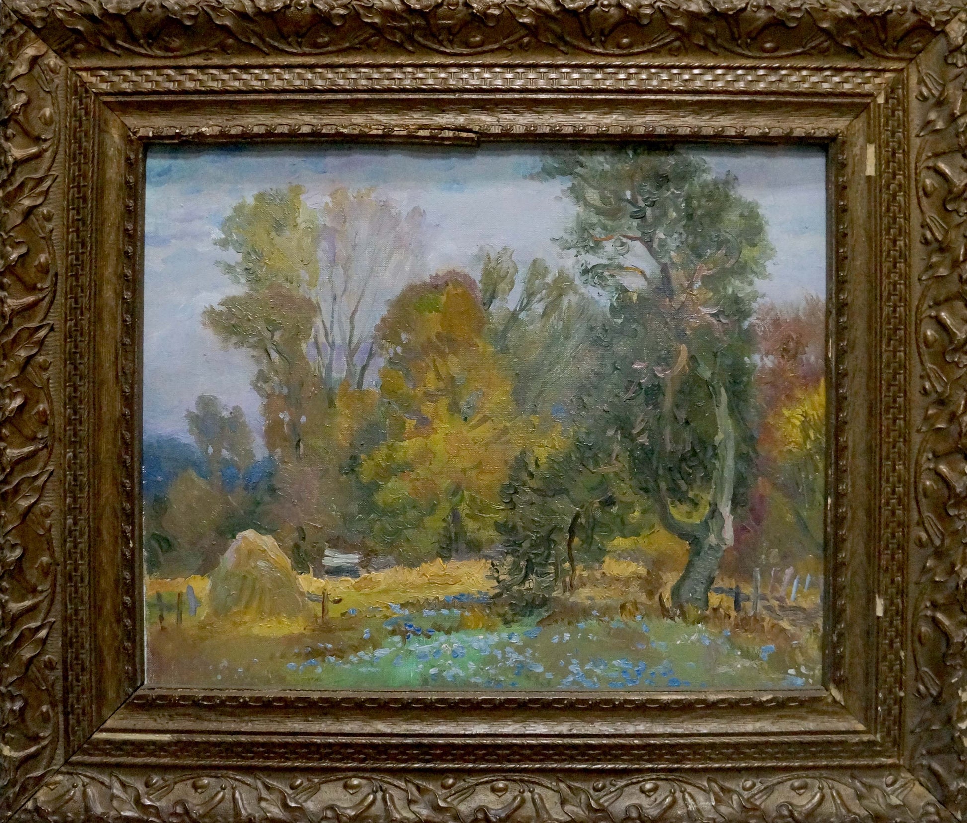Ornate gold-framed oil painting of autumn forestscape with trees and blue flowers