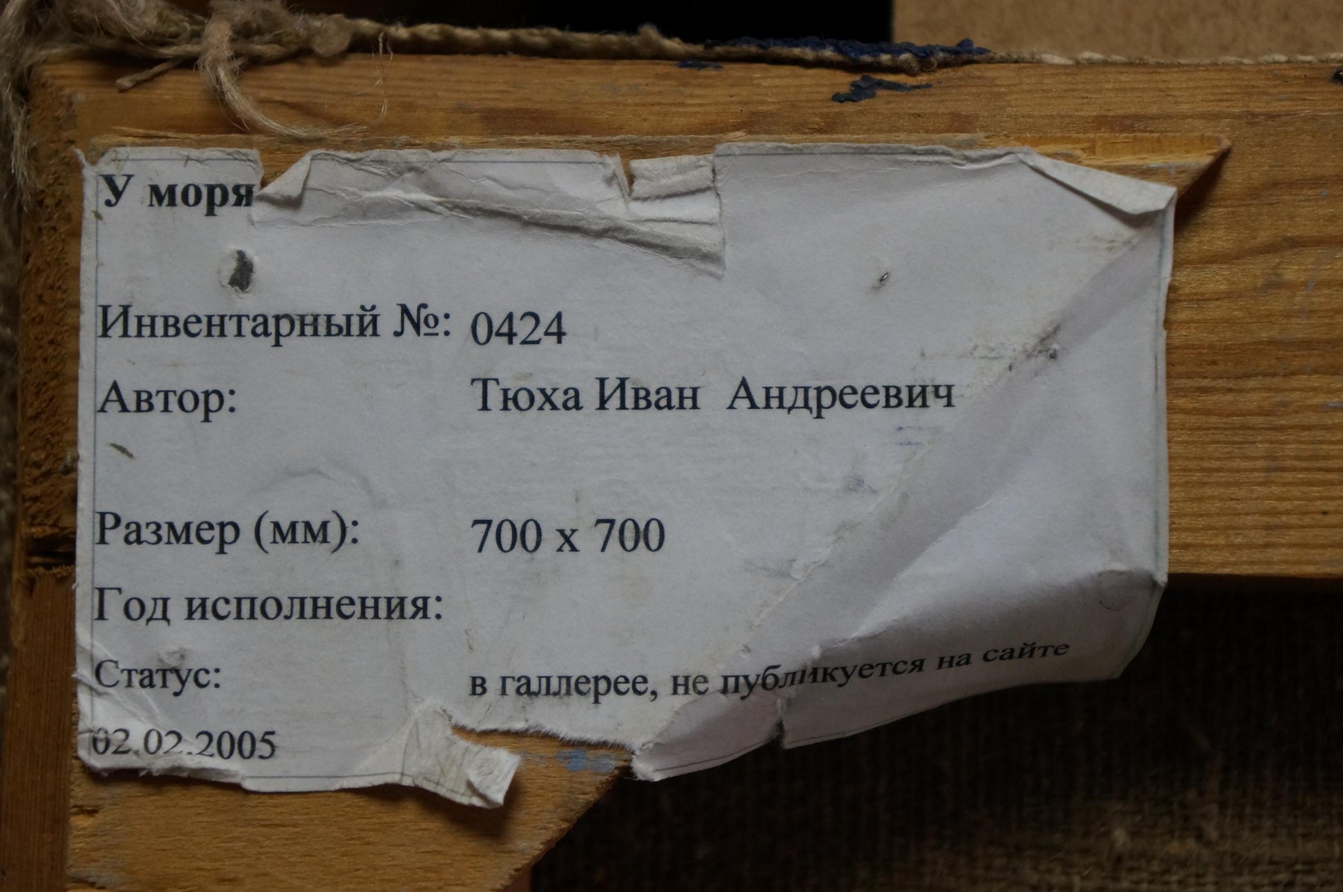 Back of Oil painting By the sea Tyukha Ivan Andreevich: torn label with Cyrillic text on wood