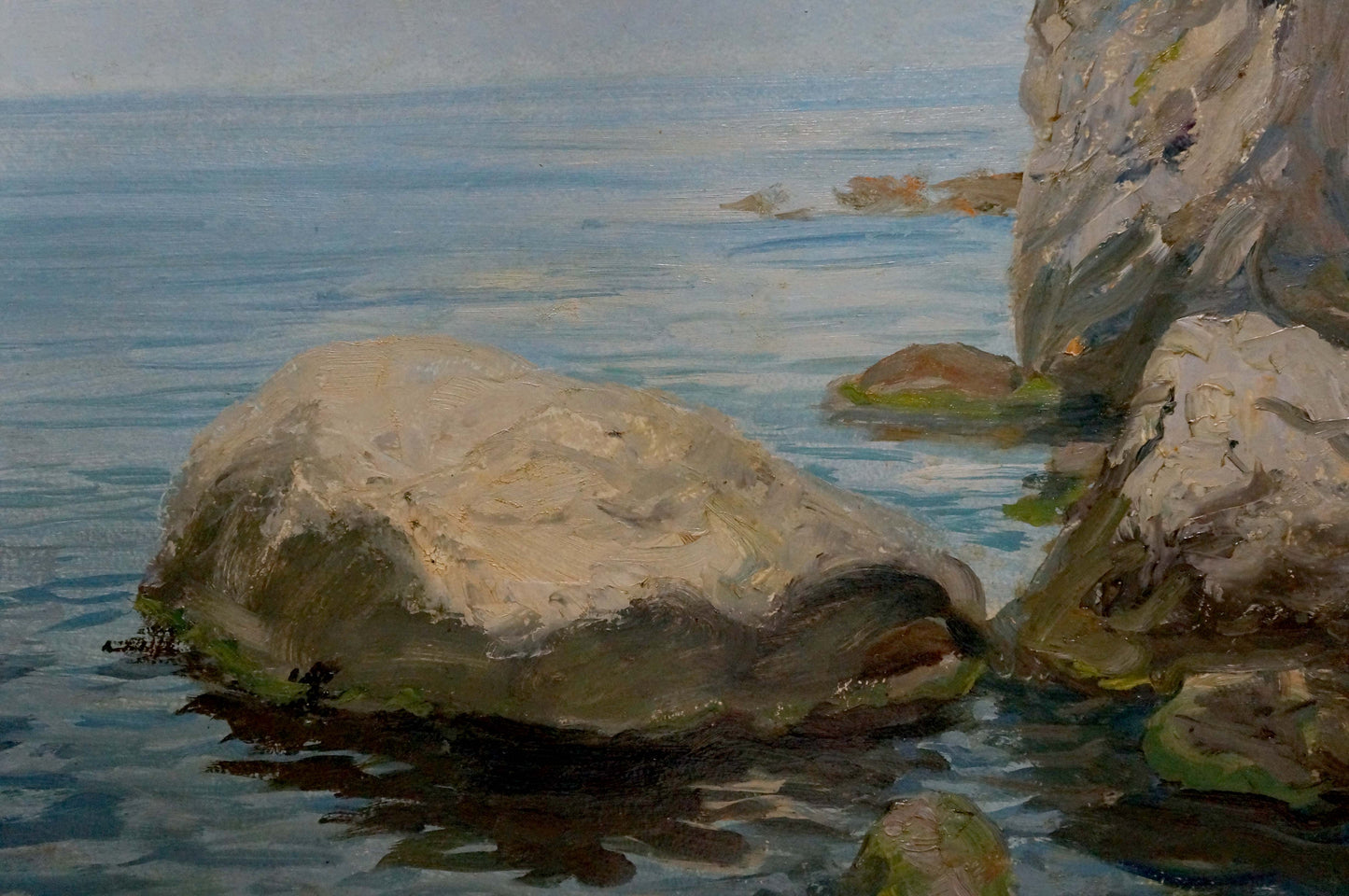 Oil painting of weathered gray rock with moss in calm blue seashore water