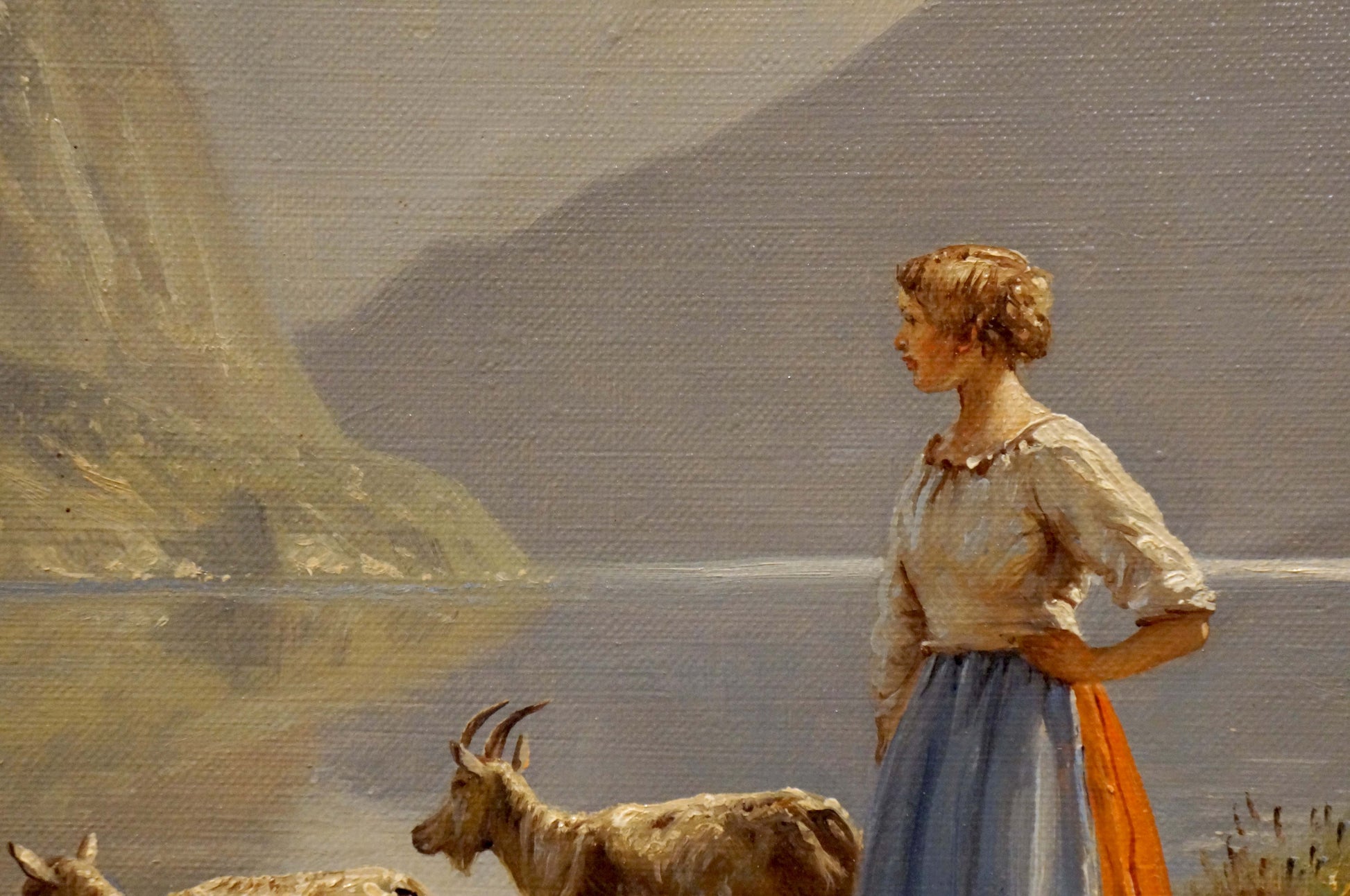 Oil painting by Louis Böhm: woman in white blouse, blue skirt, orange sash with goats by water