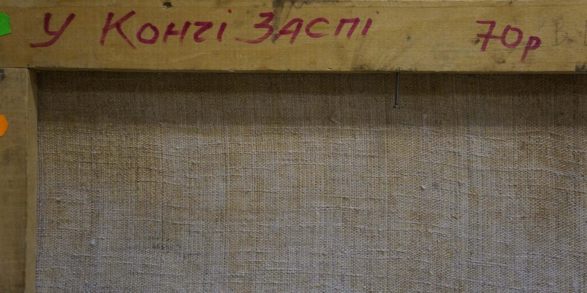 Back of Oil painting By the River by Alexander Mynka with rustic wooden frame and red Cyrillic text on burlap
