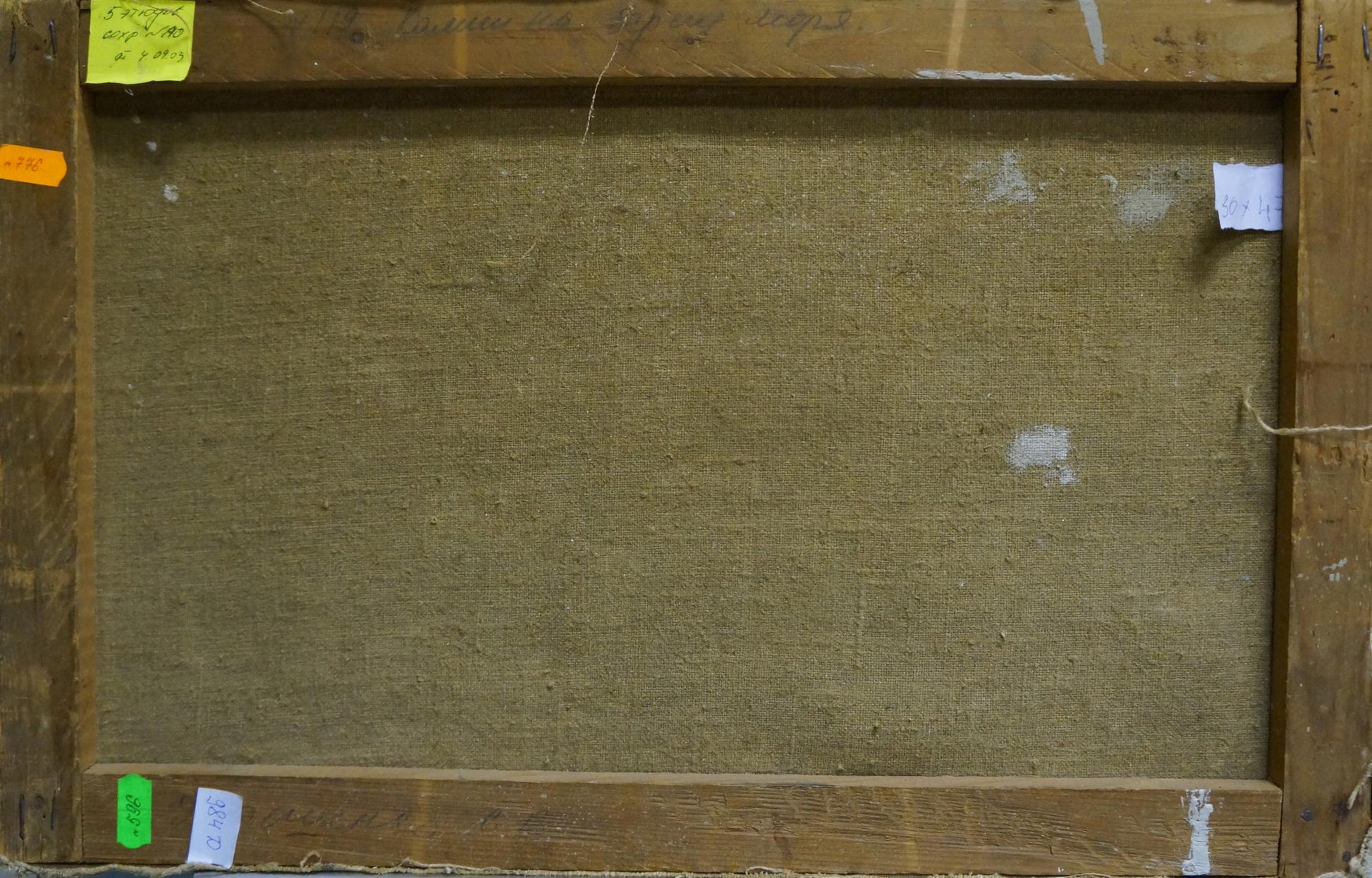 Back of framed Oil painting Stones by the sea with beige textured canvas on rustic wood