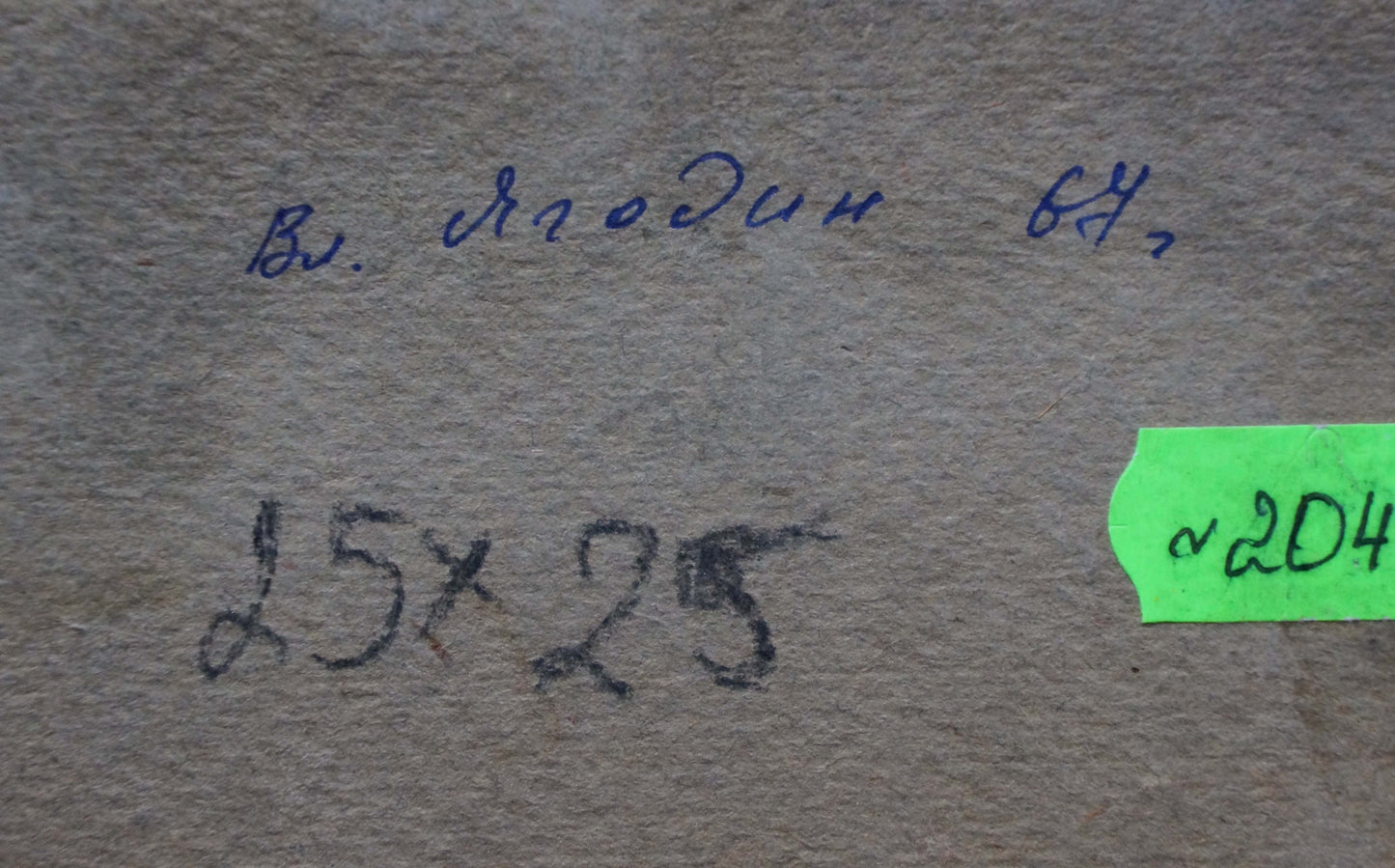 The image shows a textured, beige-colored paper surface with handwritten markings and a green label.