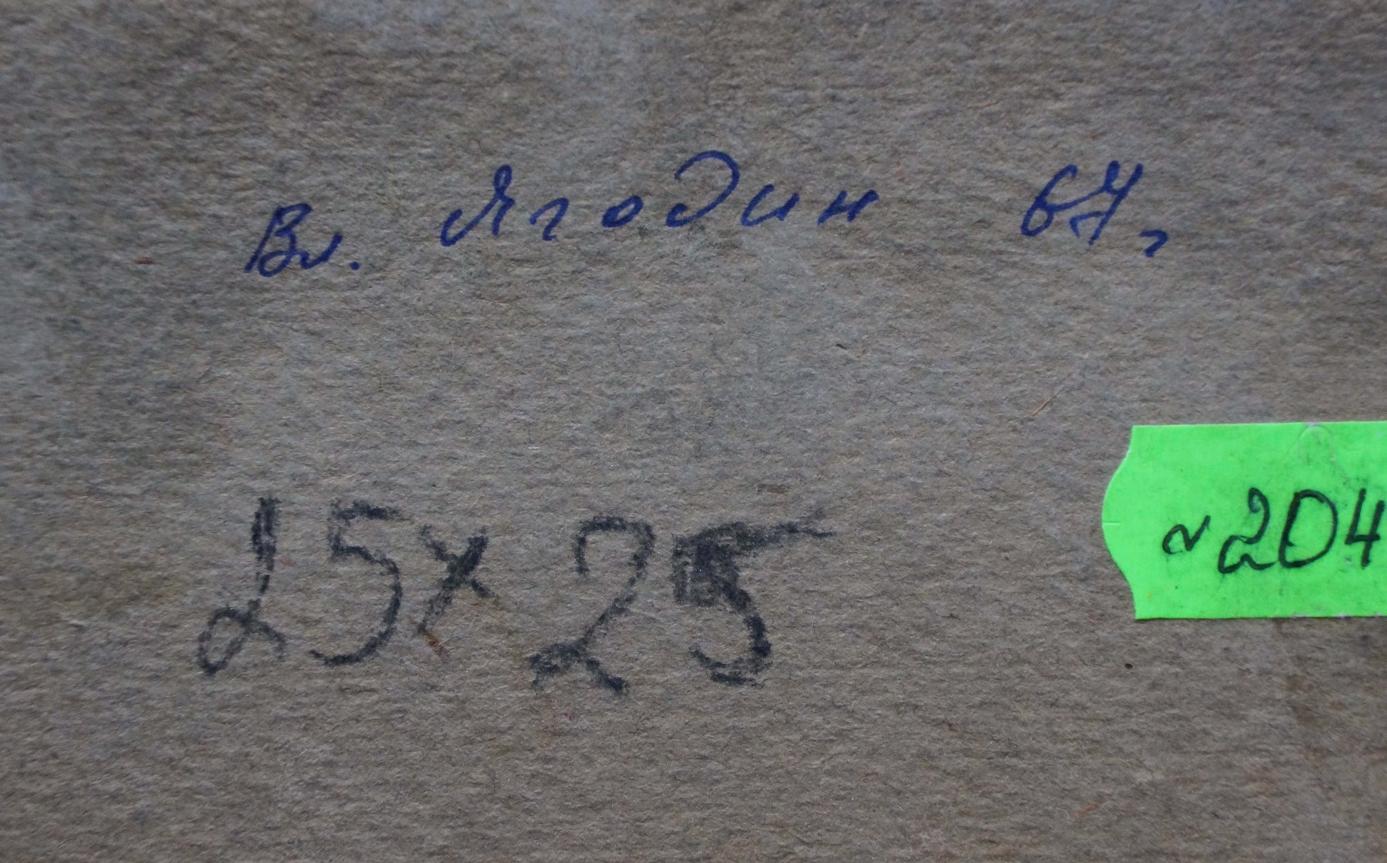 The image shows a textured, beige-colored paper surface with handwritten markings and a green label.