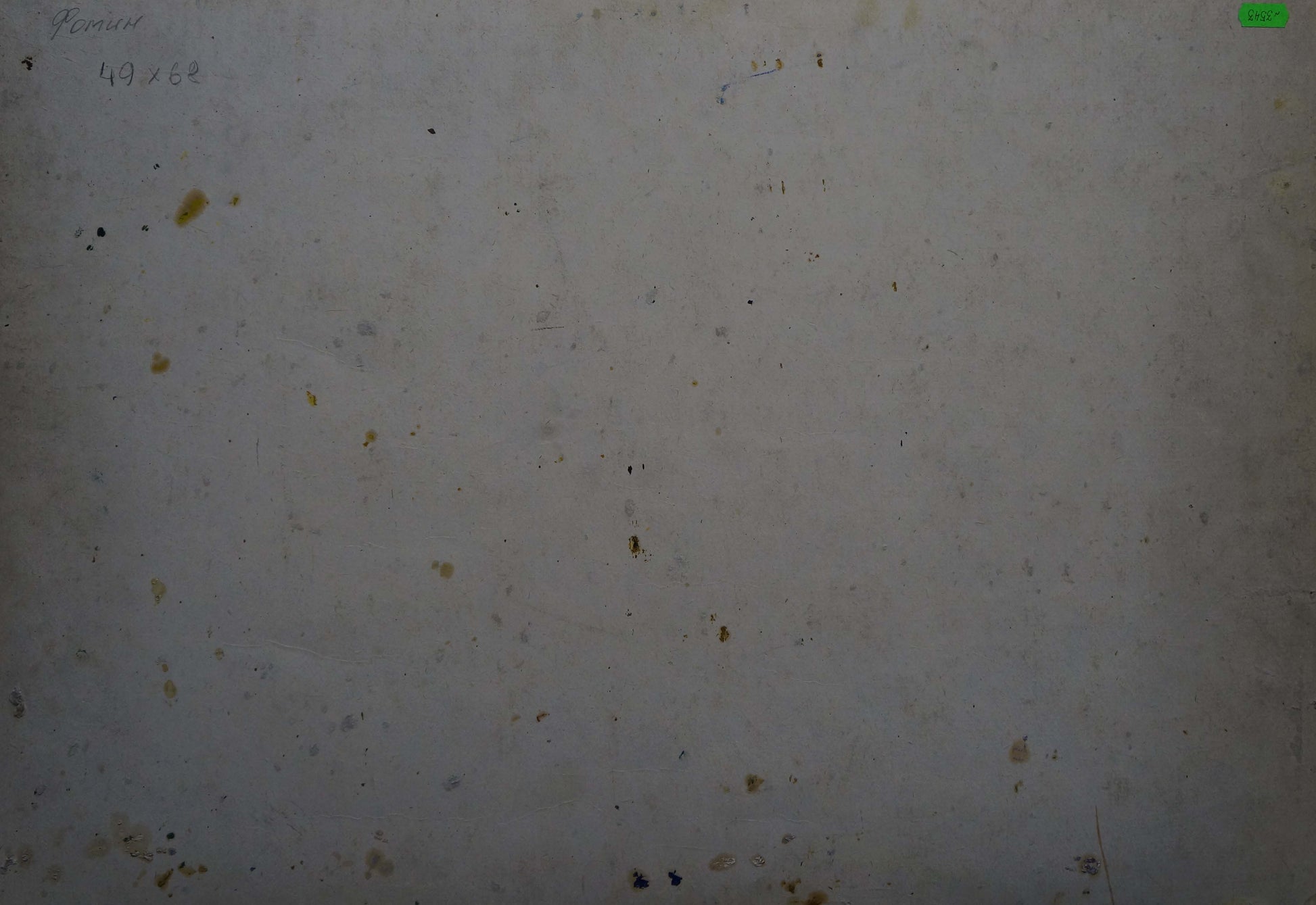 A weathered off-white surface with scattered dark and yellowish stains.