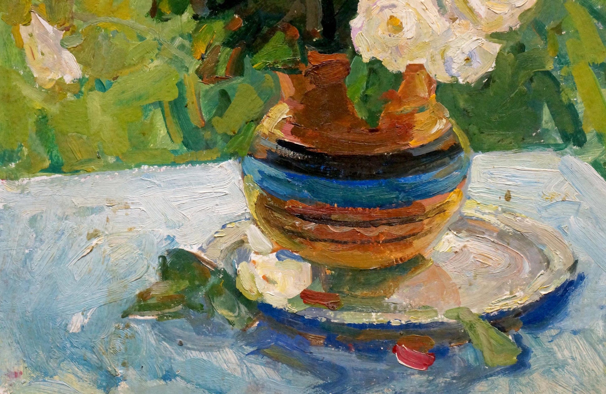 Hand-painted ceramic vase with orange, blue, brown stripes holding white roses