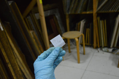 Blue-gloved hand holding white tag with measurements for Bozhiy Mikhail portrait