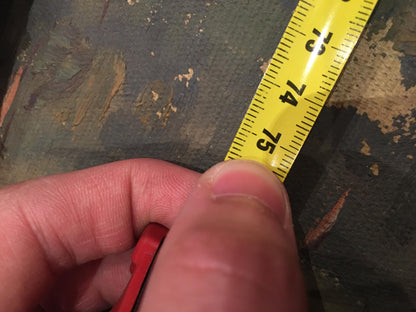 Hand holding yellow measuring tape with black markings near red casing