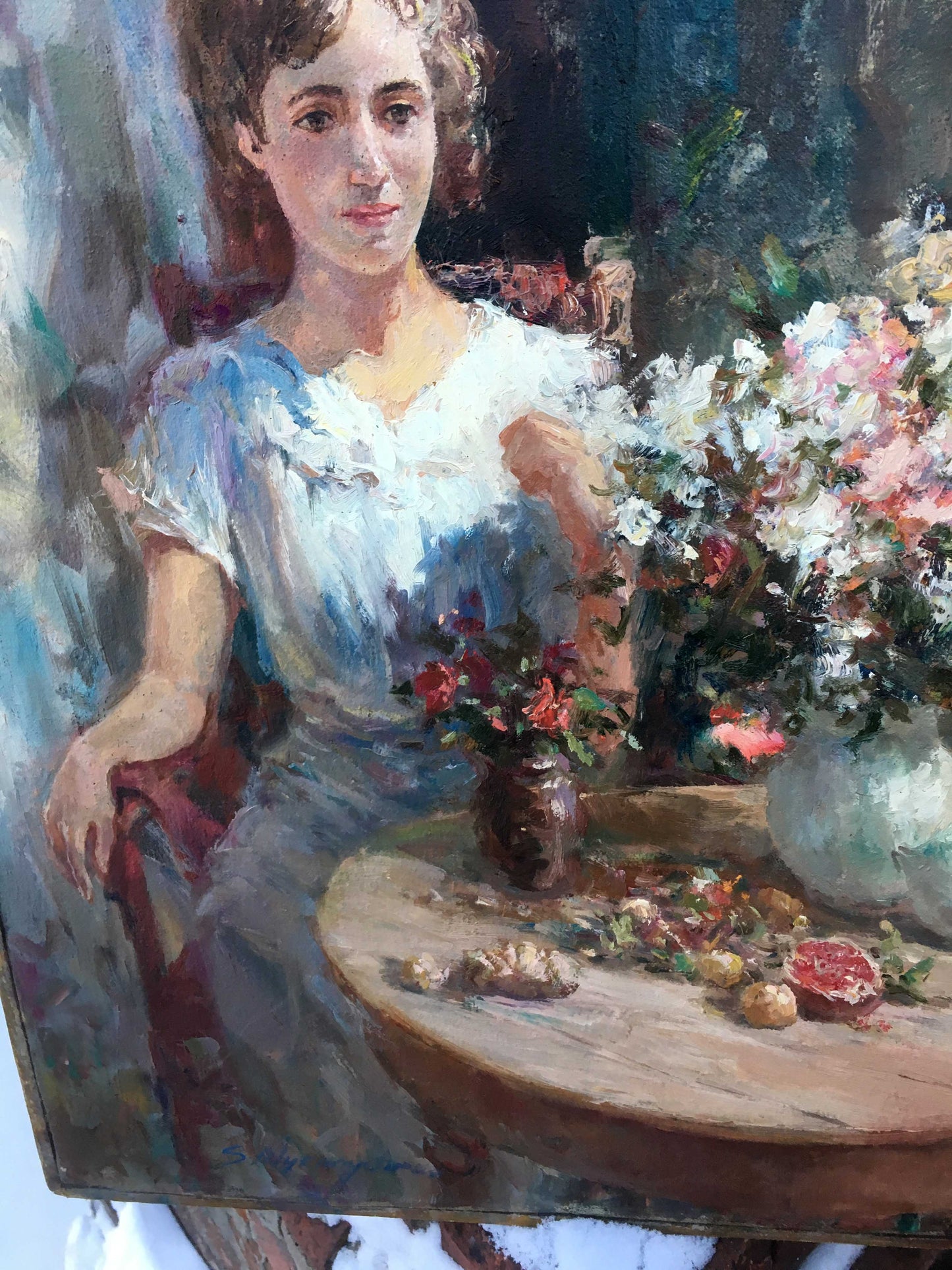 Pensive girl in white dress with blue accents by floral table oil painting
