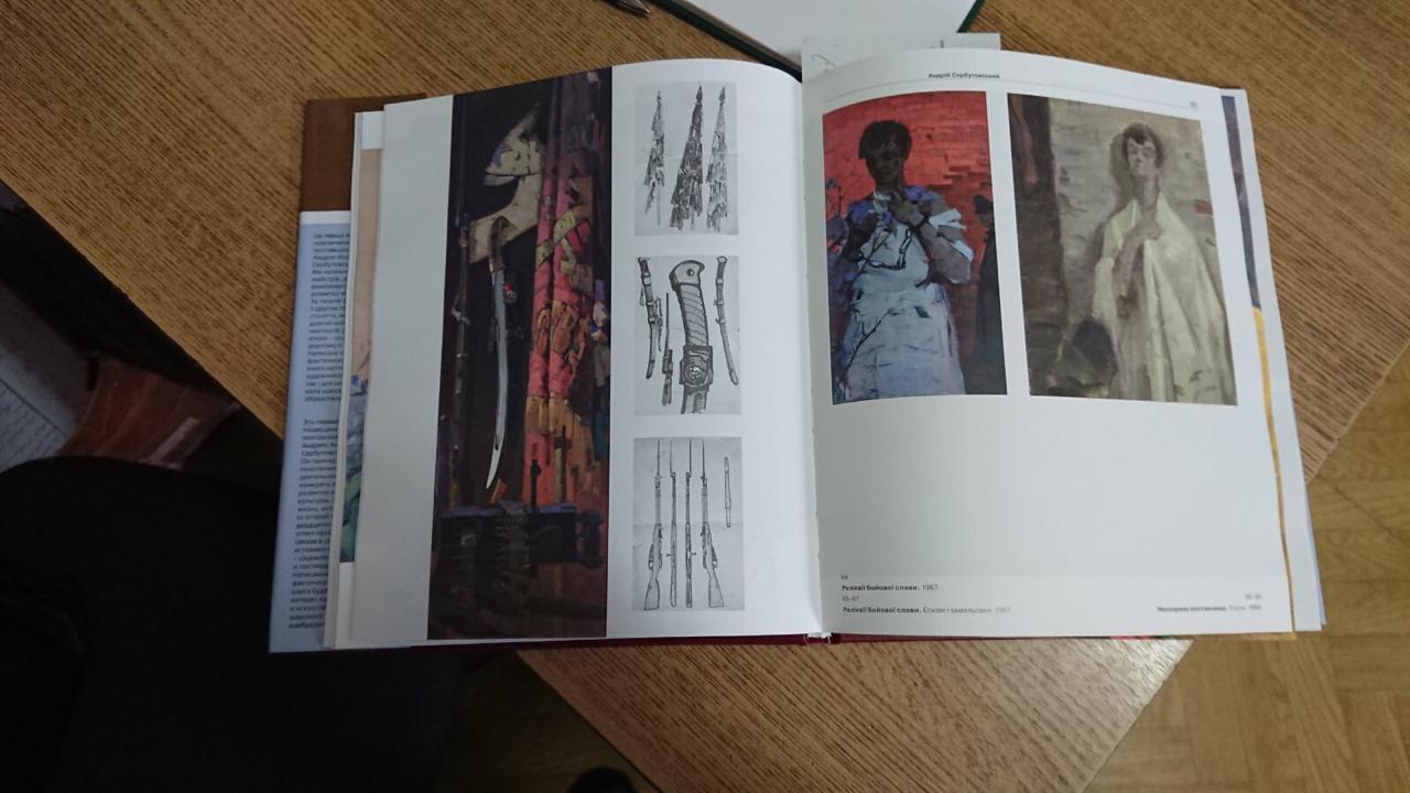 Open art book with historical weapons drawings near Serbutovsky oil painting